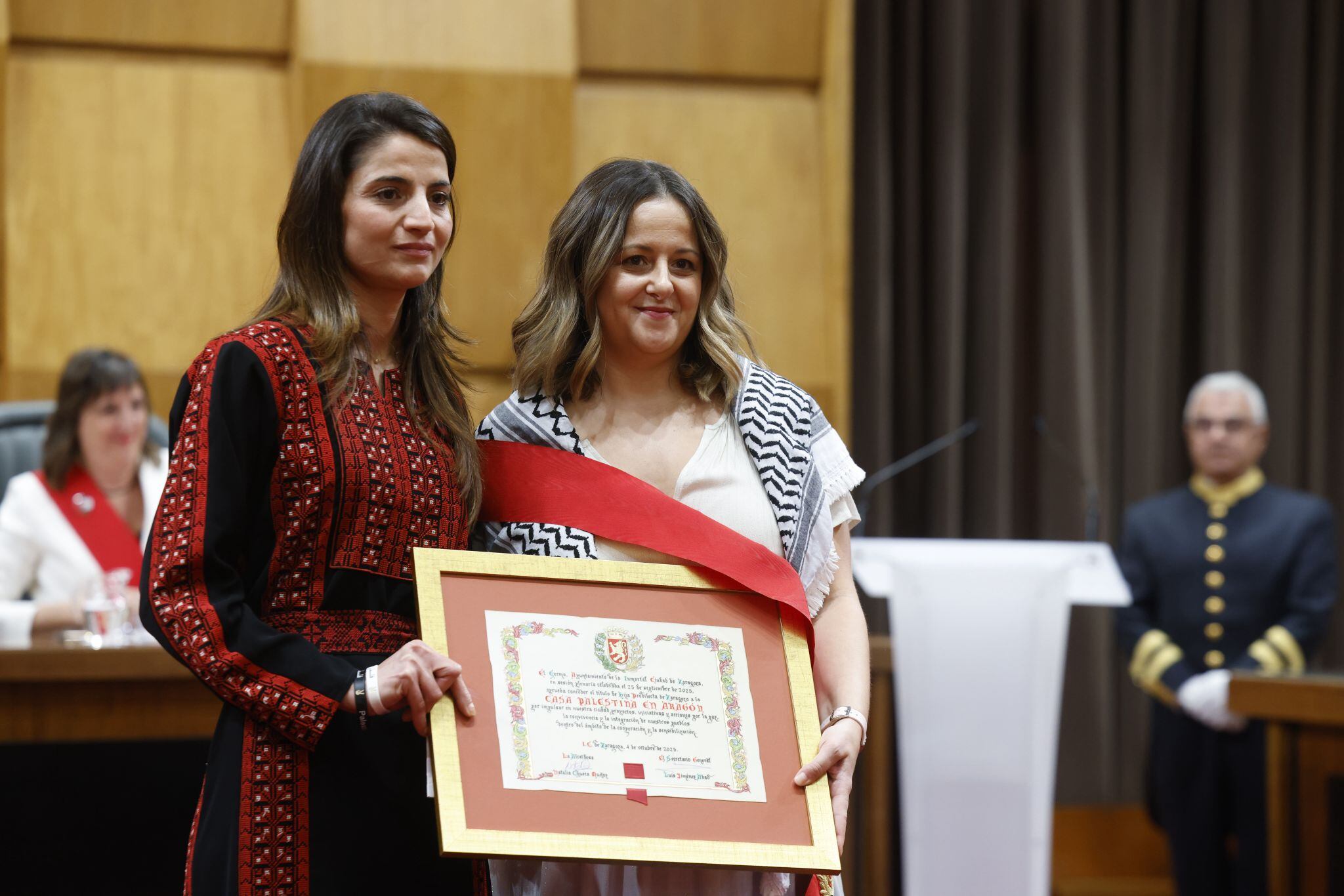 Fiestas del Pilar. Acto de la Entrega de Medallas y Distinciones de 2025 de Zaragoza. Hijos predilectos: Casa Palestina de Aragón, junto a Elena Tomás (ZEC)