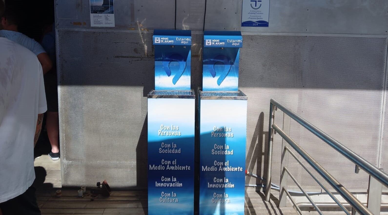 El Ayuntamiento de Alicante coloca dispensadores de agua en el acceso al ascensor del Castillo de Santa Bárbara. Durante la espera, los visitantes rellenan sus botellas de agua para refrescarse.