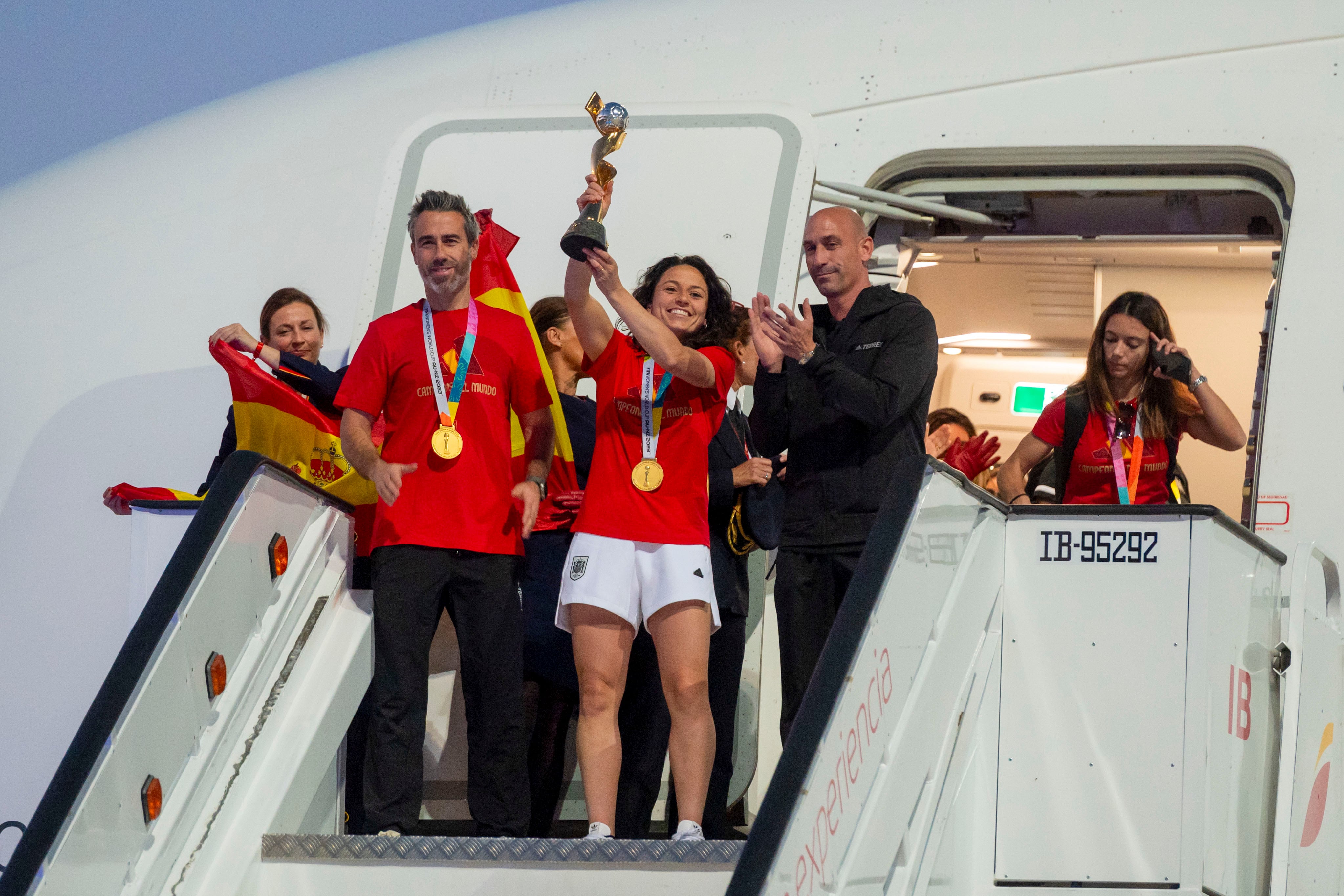 La jugadora de la selección española de fútbol Ivana Andrés (c), con el resto de sus compañeras y acompañadas por su entrenador Jorge Vilda y por el presidente de RFEF Luis Rubiales, saludan con el trofeo a su llegada al aeropuerto de Barajas, este lunes en Madrid.