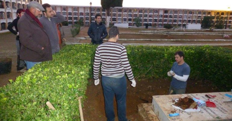 Varias personas junto a la lápida que recuerda a los enterrados en el cementerio de Marmolejo.