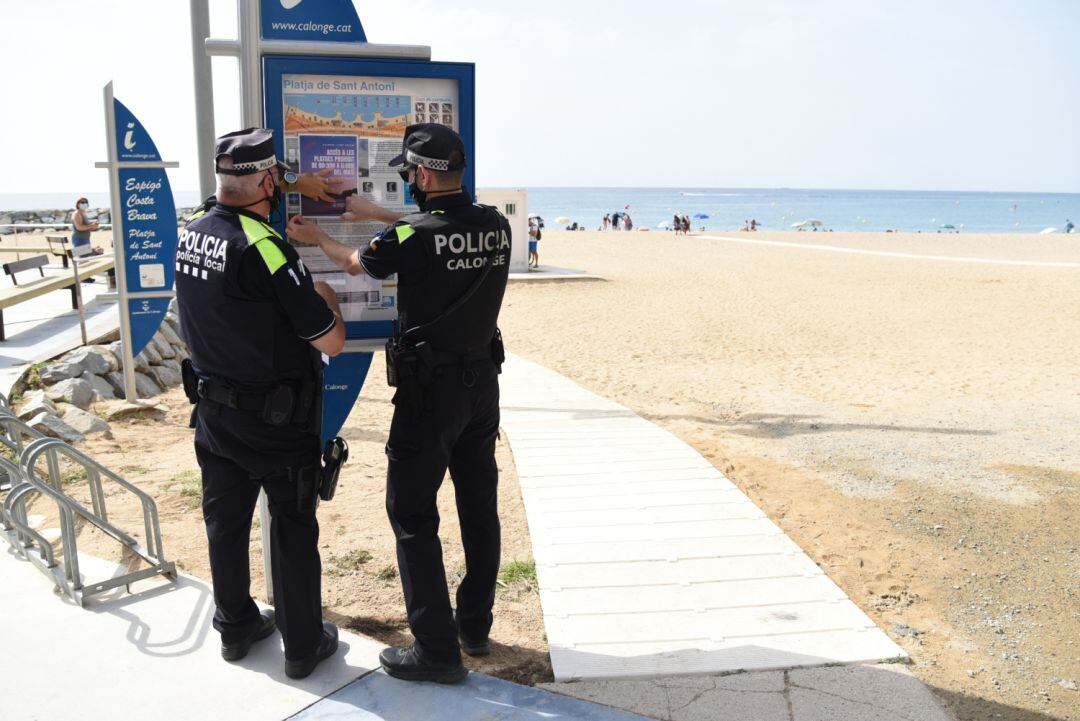 La Policia Local enganxant els cartells de senyalització de platges tancades a la nit