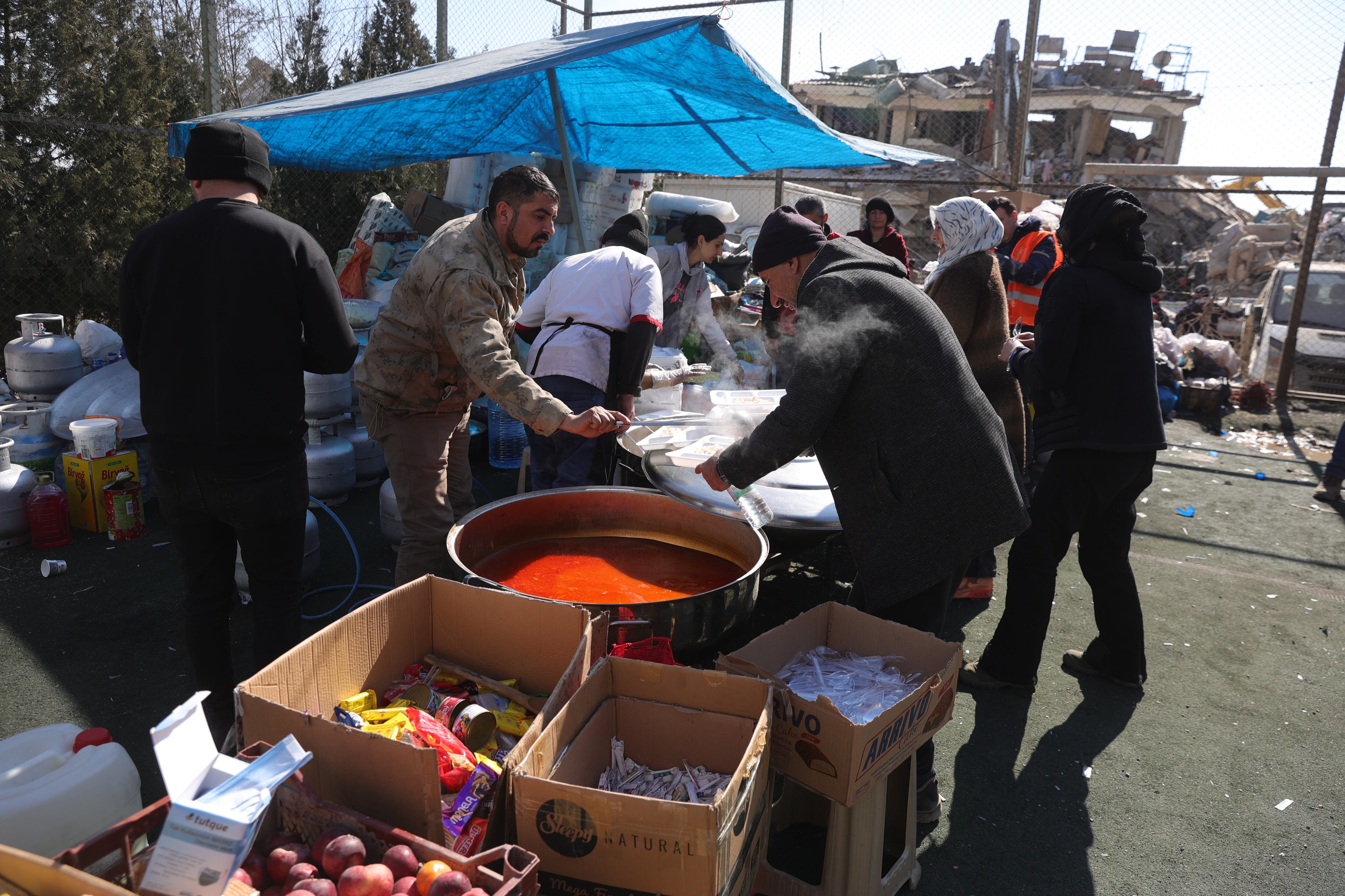 Kahramanmaras (Turkey), 11/02/2023.- Food is distributed to people affected by the earthquake near the rubble of a collapsed building in Kahramanmaras, Turkey, 11 February 2023. More than 24,000 people have died and thousands more are injured after two major earthquakes struck southern Turkey and northern Syria on 06 February. Authorities fear the death toll will keep climbing as rescuers look for survivors across the region. (Terremoto/sismo, Siria, Turquía, Estados Unidos) EFE/EPA/ABIR SULTAN
