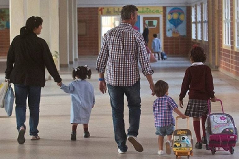 Un padre y una madre recogiendo a sus hijos a la salida del colegio.