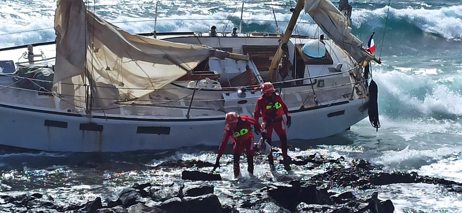 Bomberos junto al velero encallado en la costa de Puerto del Carmen, en Lanzarote.