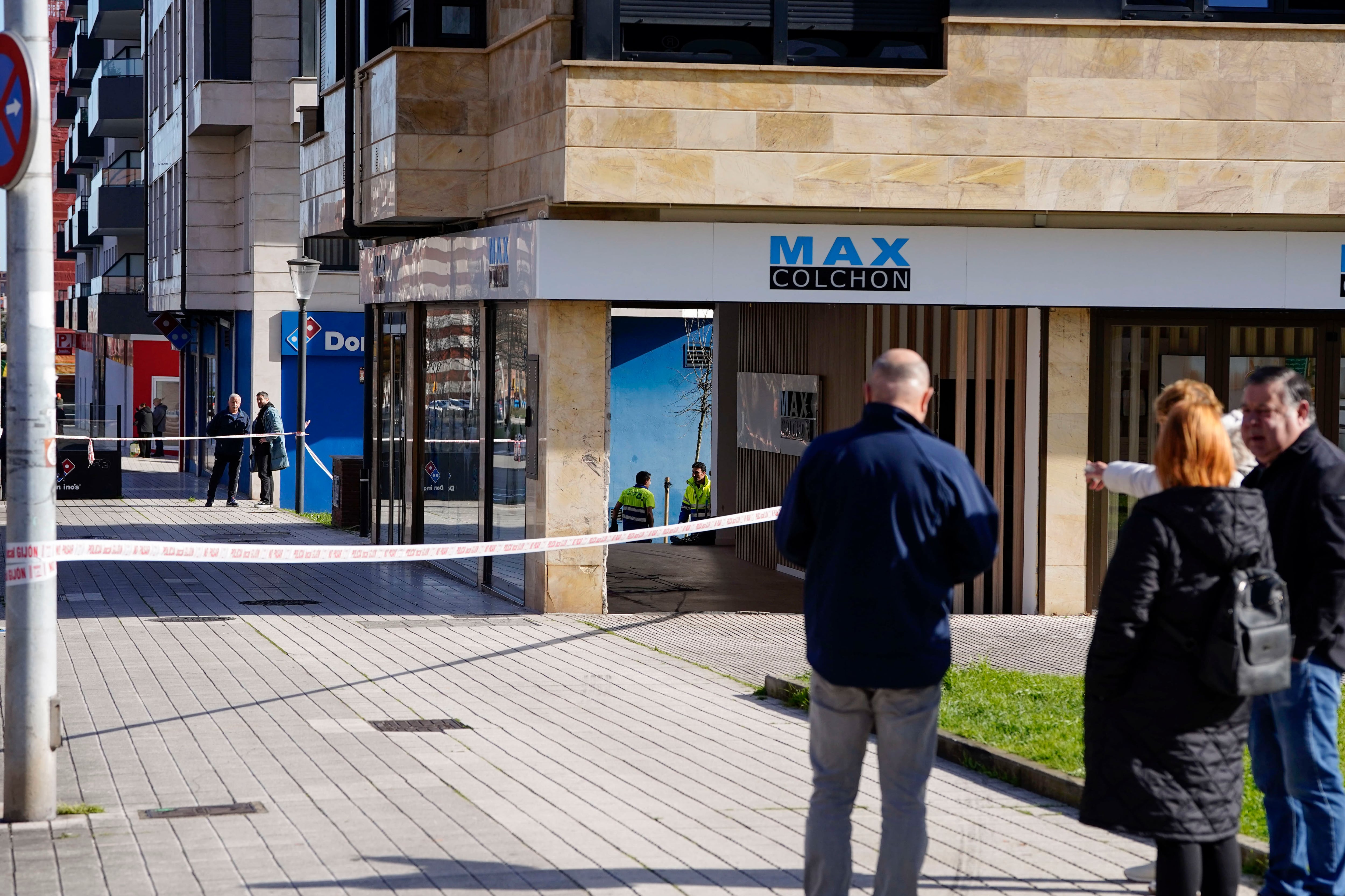 OVIEDO, 21/02/2026.- Operarios recogen restos del accidente en el que dos personas fallecieron este viernes en Gijón (Asturias) tras el "síncope" sufrido por el conductor de una grúa municipal que acabó atropellando a un peatón, según informa el Ayuntamiento de la ciudad. El conductor de la grúa municipal se encontraba transportando una furgoneta por la avenida de Oviedo, en dirección a la avenida Constitución, sobre las 21:45 horas, cuando sufrió un síncope y acabó chocando ambos vehículos contra un establecimiento y atropellando a su paso a un peatón que se encontraba en la misma acera. EFE/Paco Paredes