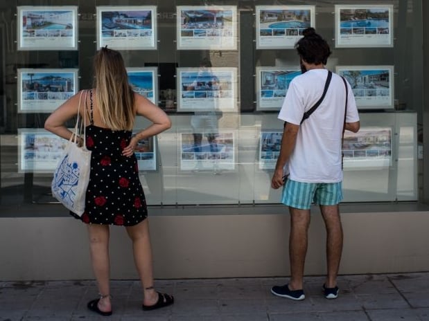 Archivo - Dos personas observan inmuebles en alquiler y en venta en un escaparate de una inmobiliaria ubicada en Palma.