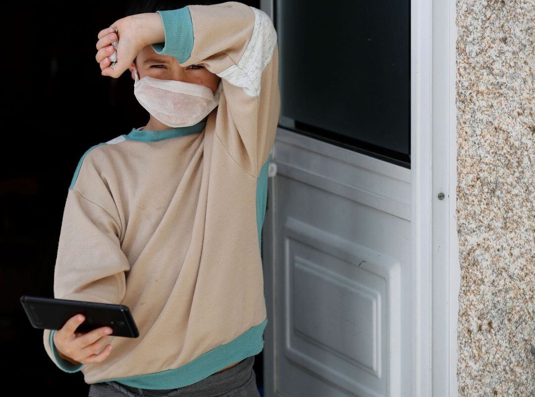 Un niño con una mascarilla casera a las puertas de su casa en Lugo