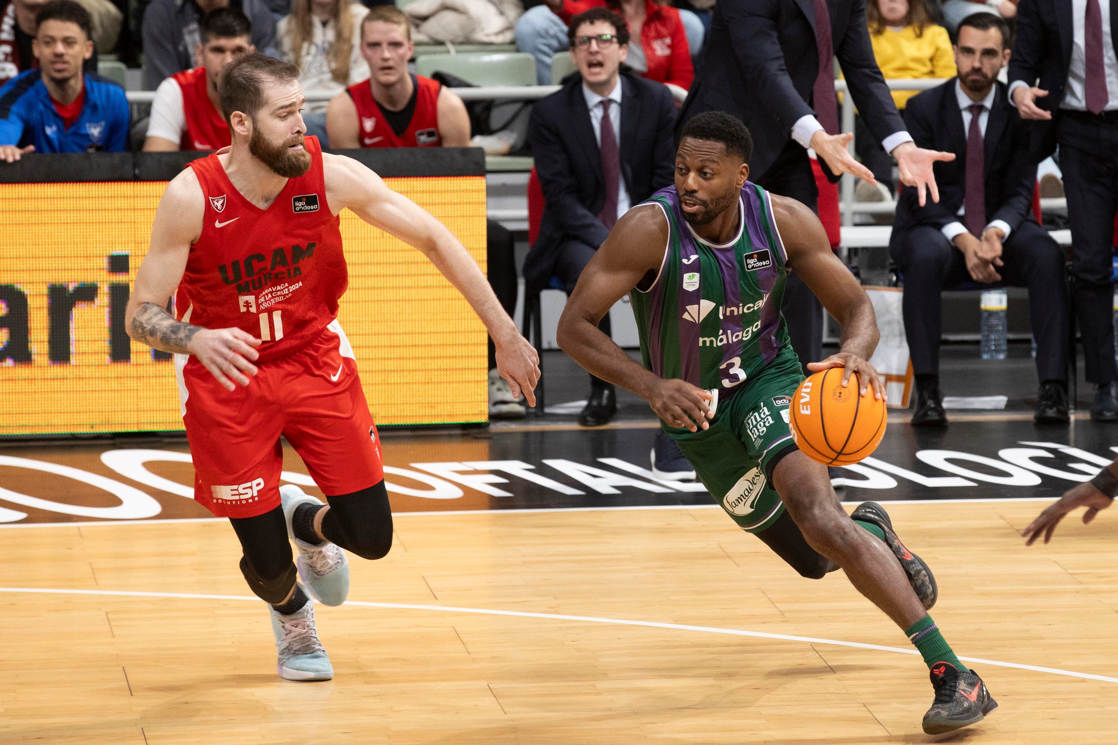 MURCIA, 02/01/2025.- El alero nigeriano de Unicaja Melvin Ejim (d) controla el balón ante el escolta montenegrino de UCAM Murcia Nemanja Radovic (i), durante el partido de la décimo cuarta jornada de la liga Endesa que están disputando este jueves en el Palacio de los Deportes de Murcia. EFE/Marcial Guillén
