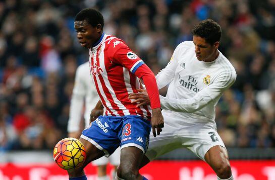 GRA169. MADRID, 17/01/2016.- El defensa del Real Madrid, Raphael Varane (d) pelea un balón con el centrocampista camerunés del Sporting Daniel Ndi (i) durante el partido de la vigésima jornada de liga en Primera División disputado esta tarde en el estadio