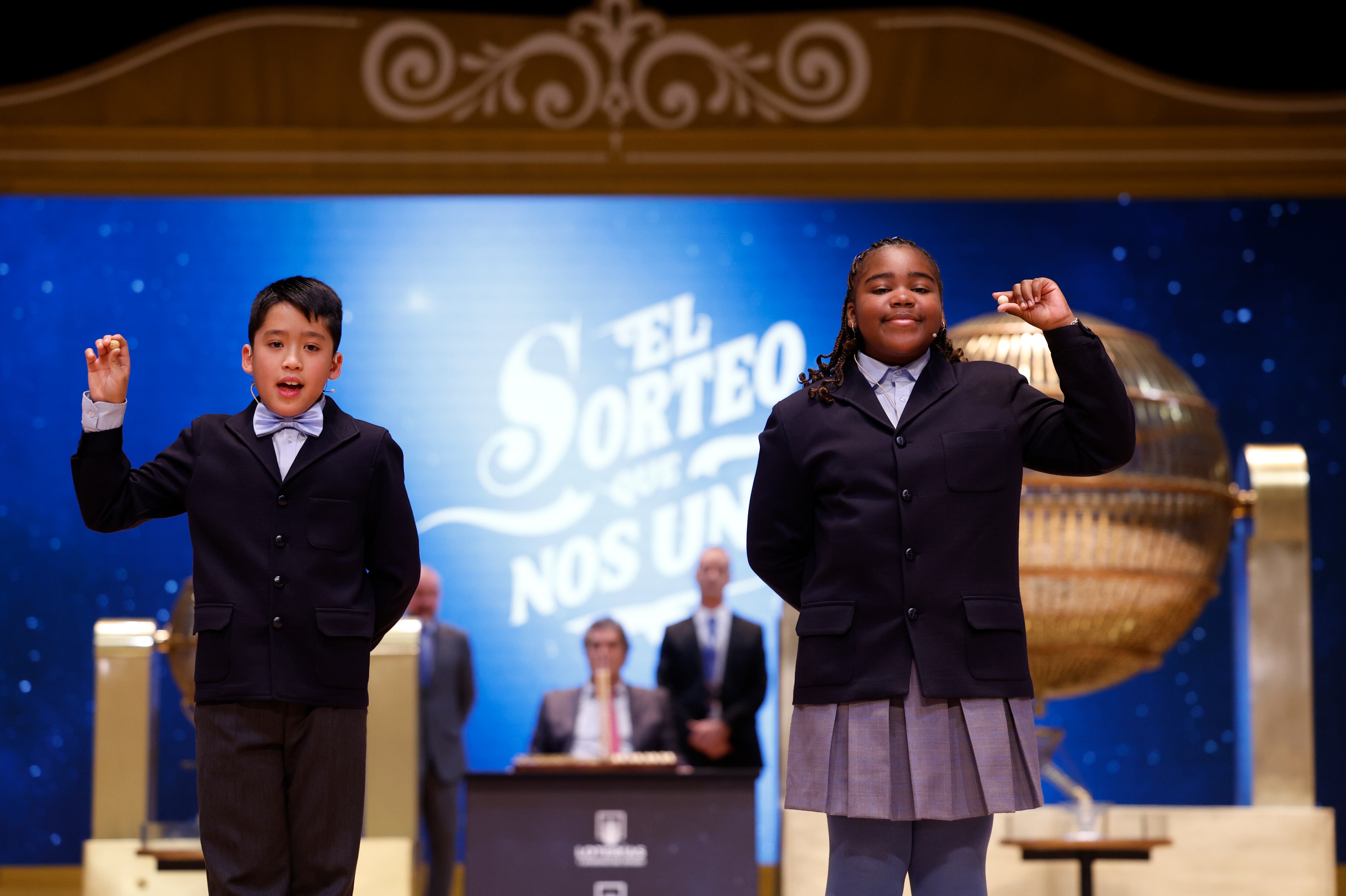 MADRID, 22/12/2024.- Los niños de la Residencia San Ildefonso de Madrid Ainhoa Rosero (d) y Axiel Kyron (i) muestran el 77.768, un cuarto premio, 200,000 euros por serie, durante el sorteo de la Lotería de Navidad que se celebra este domingo en el Teatro Real, en Madrid. EFE/Javier Lizón
