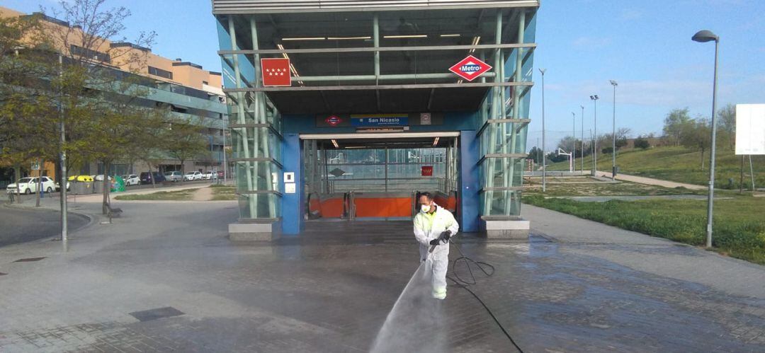 Un operario de un equipos municipal limpia a fondo y desinfecta la entrada a la estación de Metrosur de San Nicasio