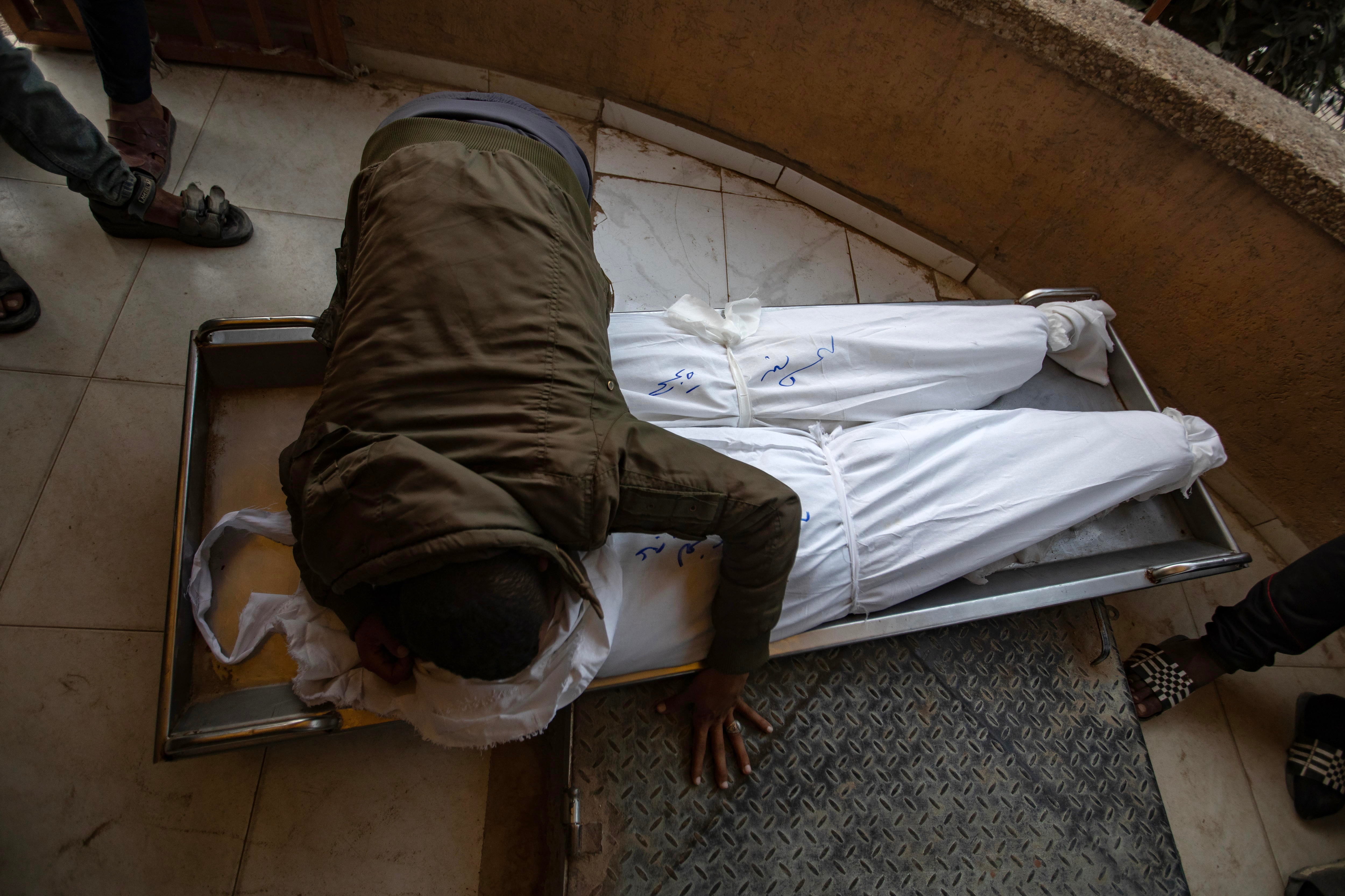 Un hombre llora sobre los cuerpos de sus familiares muertos en un ataque israelí en Gaza.