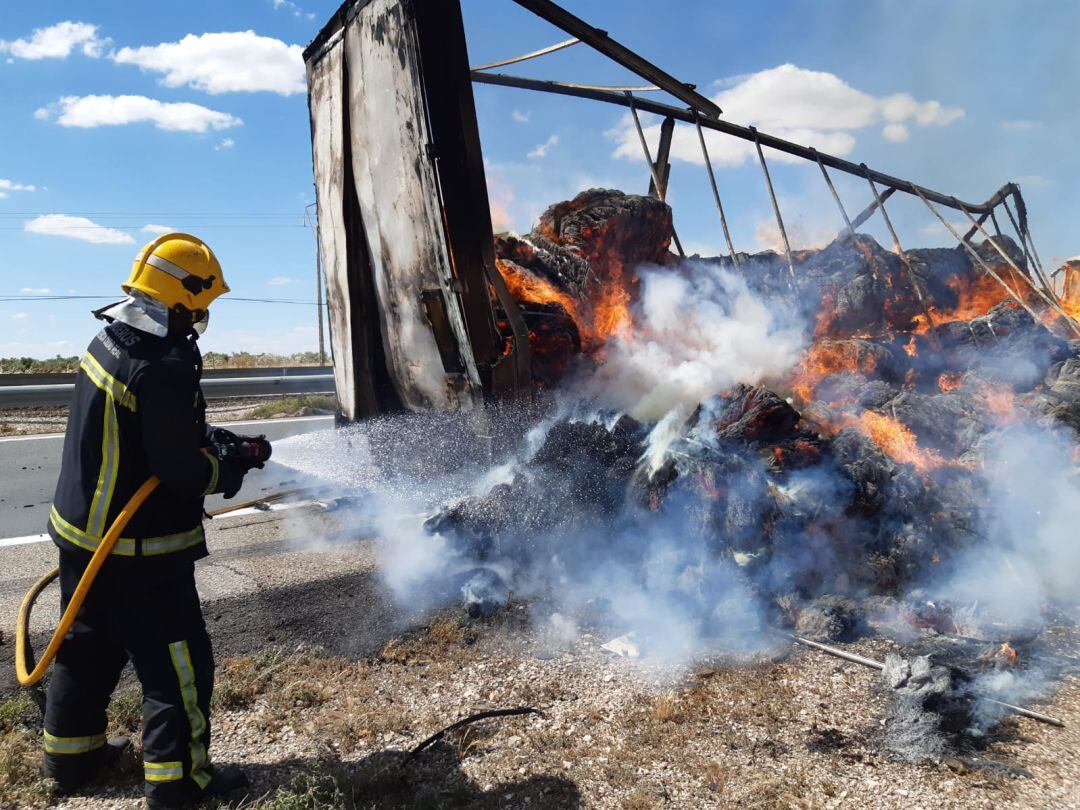 Agente de bomberos apaga las pacas de paja del camión