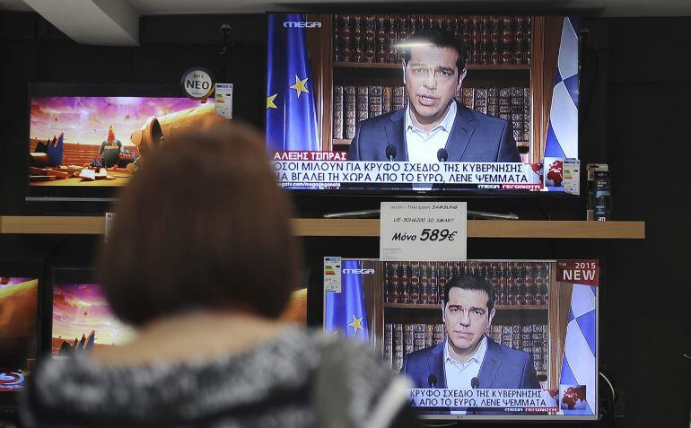 Una mujer observa en una tienda el discurso televisado del primer ministro griego, Alexis Tsipras en Atenas