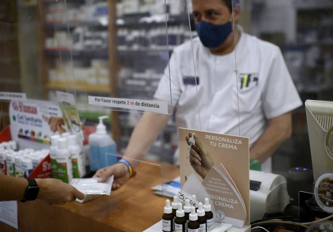 Un farmacéutico entrega a un cliente una de las mascarillas KN95.
