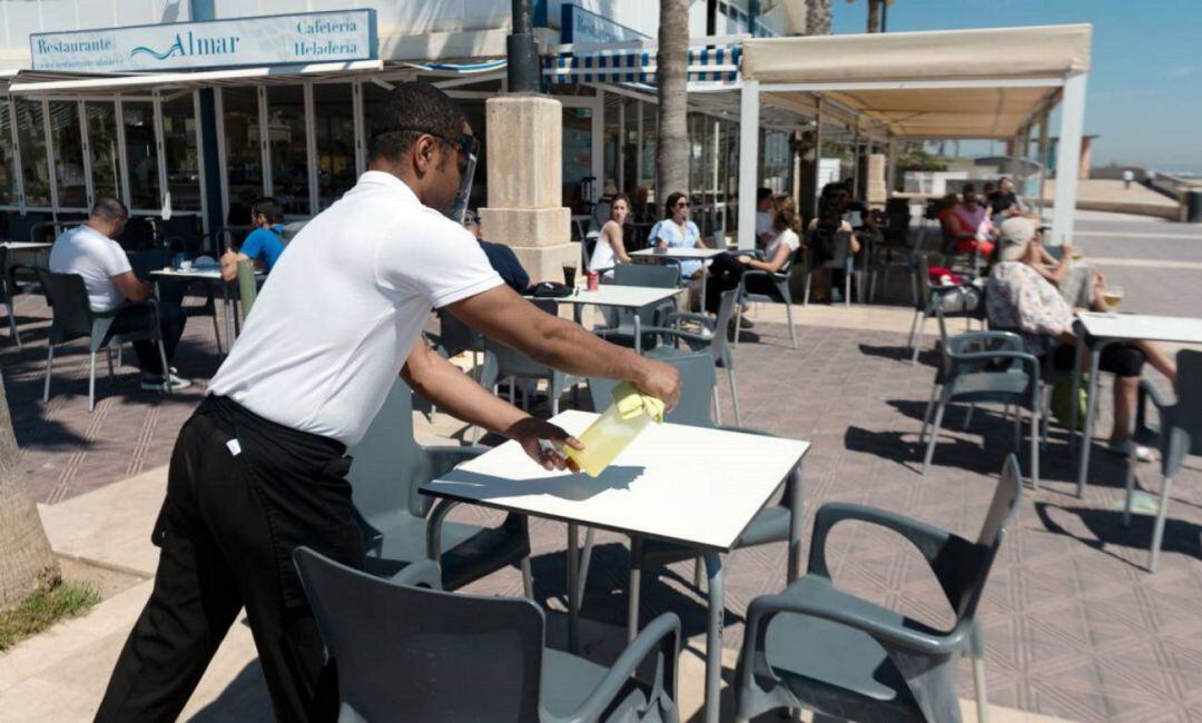 Un camarero desinfectando una mesa en un local