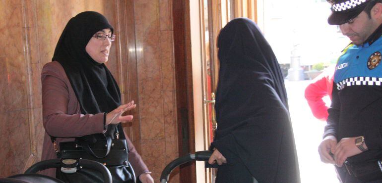 Una dona musulmana explicant a una companya amb burca que no pot entrar a l'Ajuntament. 