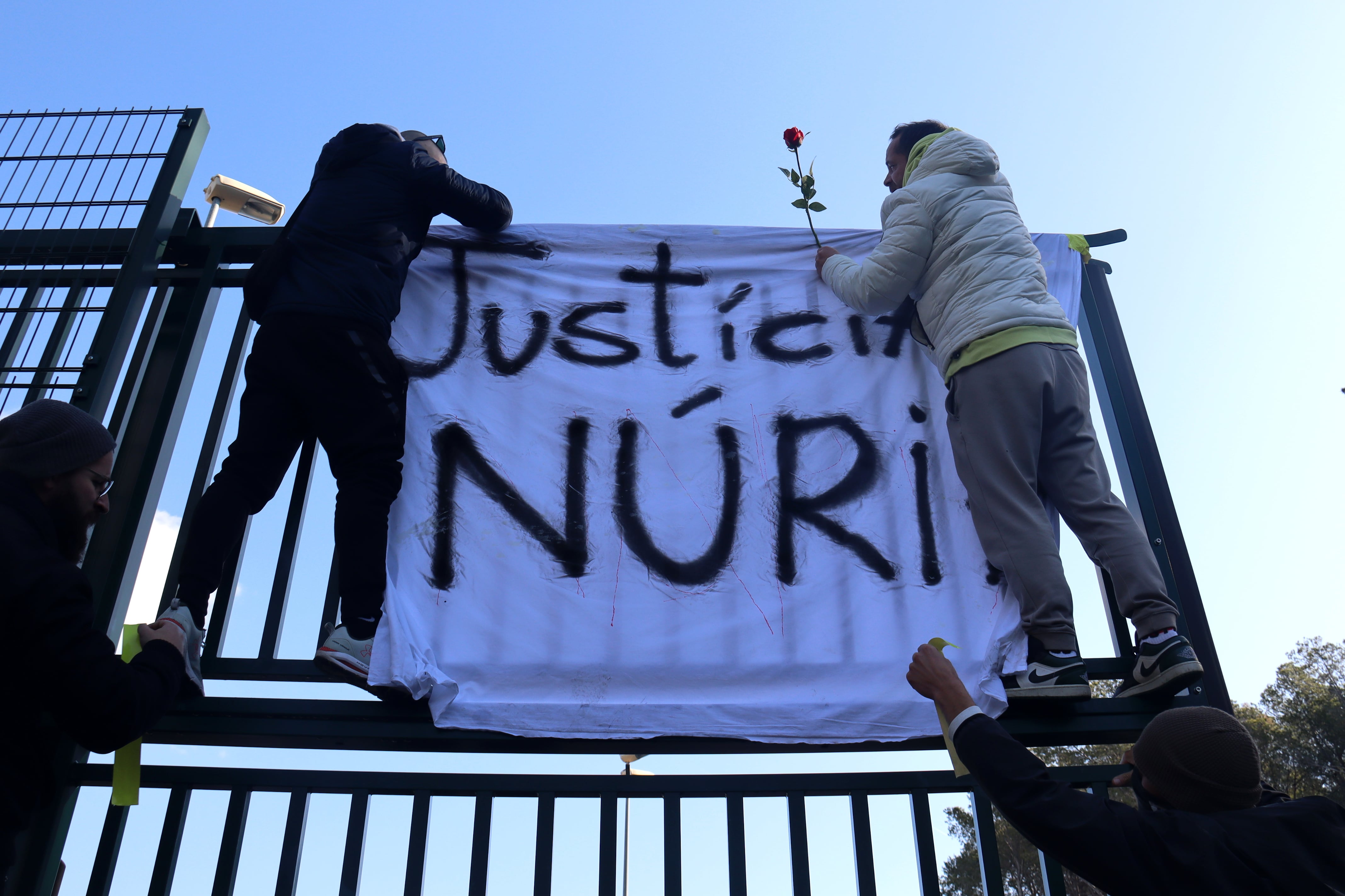 Dos treballadors de Mas d&#039;Enric penjant una pancarta i una rosa a les portes del centre penitenciari