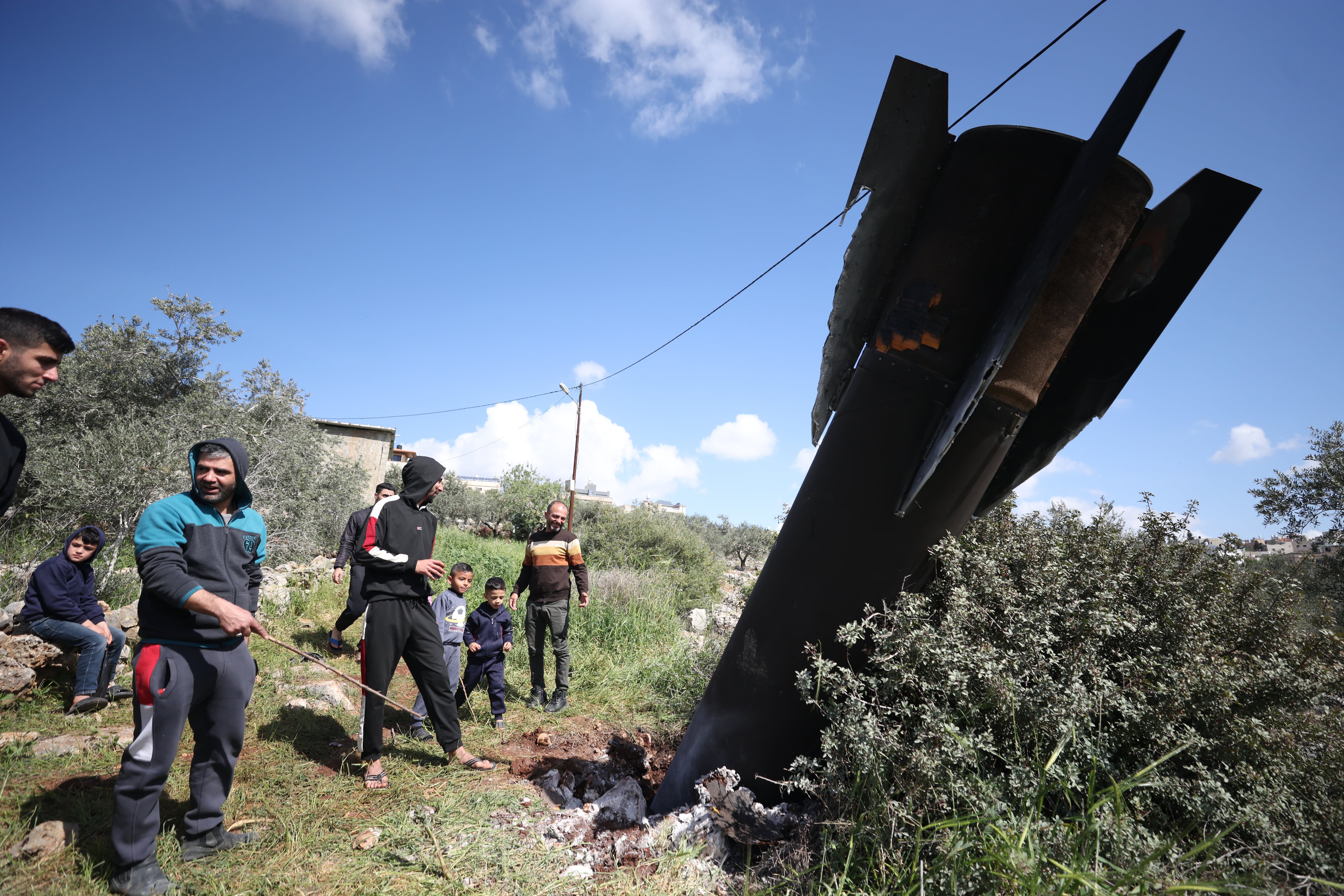 Palestinos inspeccionan los restos de un misil balístico que cayó en la aldea de Haris, en Cisjordania