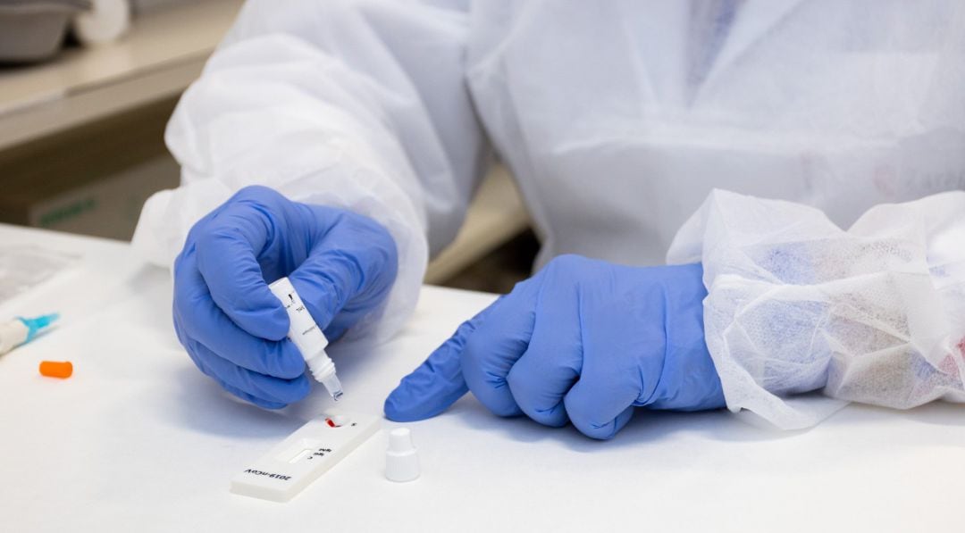 Una manos de sanitario con guantes de nitrilo realizan un test