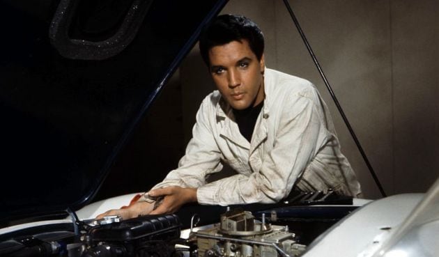 Elvis Presley mira bajo el capó de su coche en una escena de la película &#039;Speedway&#039; de 1968.