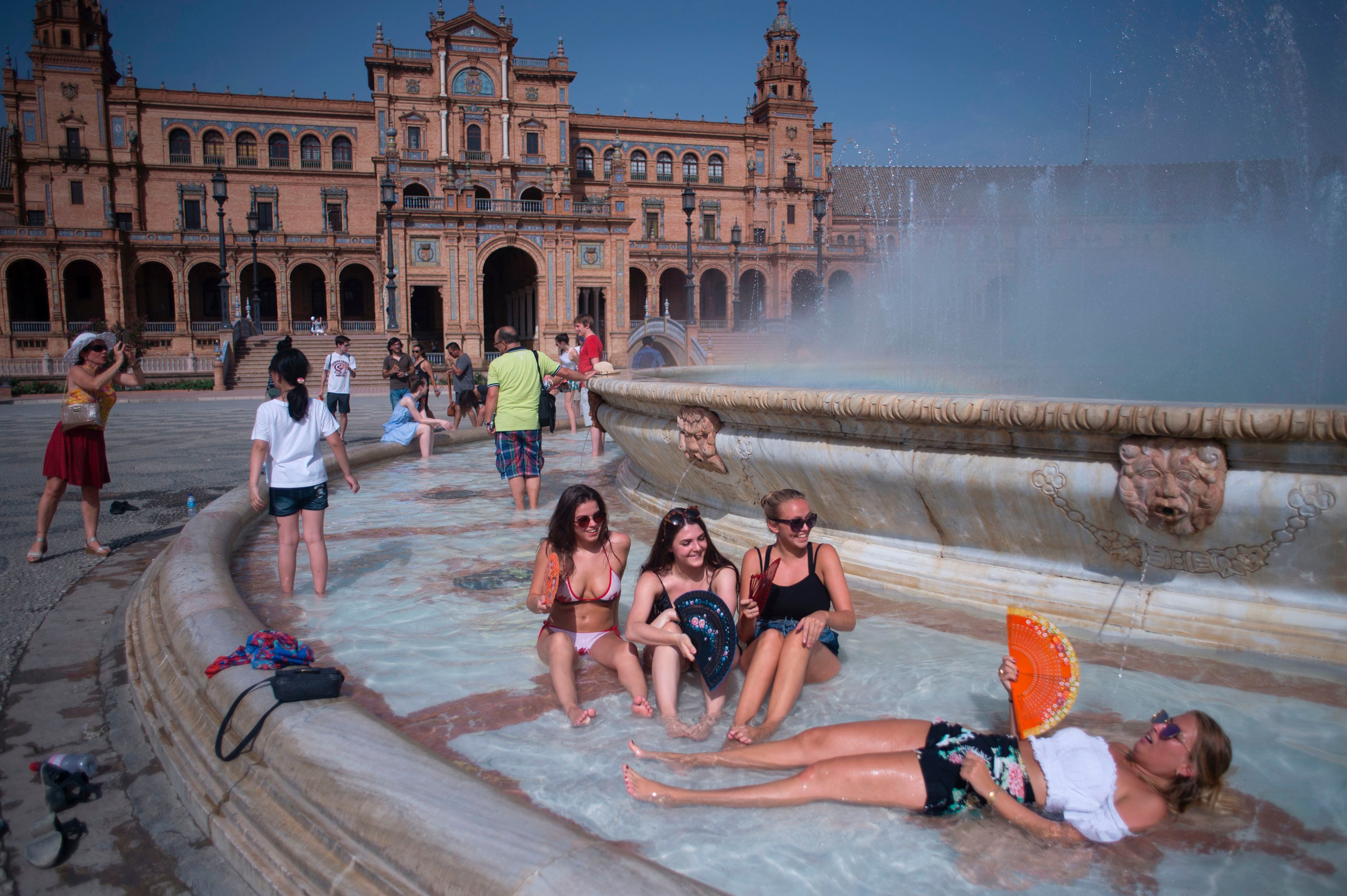 Un grupo de jóvenes se refresca en la plaza de España de Sevilla.