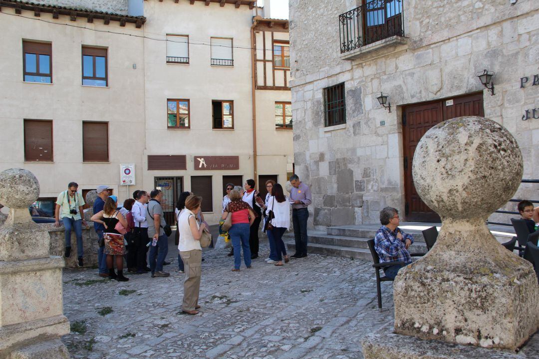 Un grupo de turistas atiende las explicaciones de la guía durante una visita guiada por la localidad en verano