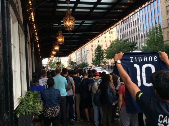 Un joven sostiene la camiseta de la selección francesa con el nombre de Zidane en la entrada del hotel del Real Madrid