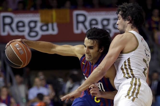 El base del Real Madrid Sergio Llull defiende la acción del base del Barcelona Víctor Sada durante el quinto partido del Play off final de la liga ACB que se disputa en el Palau Blaugrana.