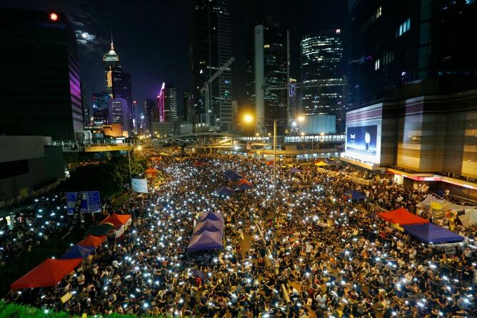 Los manifestantes prodemocráticos cantan y agitar sus teléfonos móviles mientras bloquean una carretera principal durante una manifestación frente a la sede del gobierno en Hong Kong