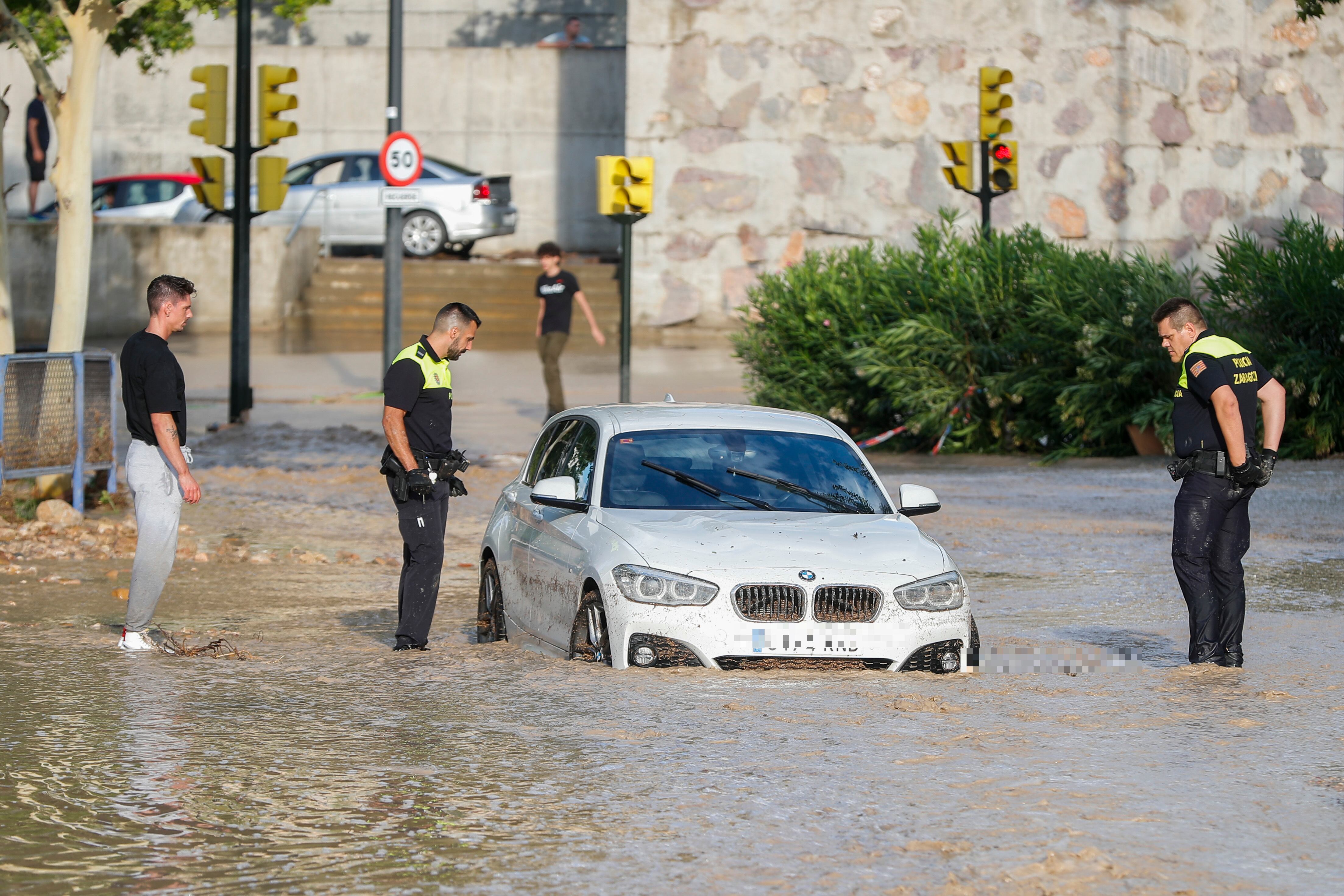 Agentes de la Policía Local observan un coche arrastrado por la tormenta caída de julio de 2023 en Zaragoza