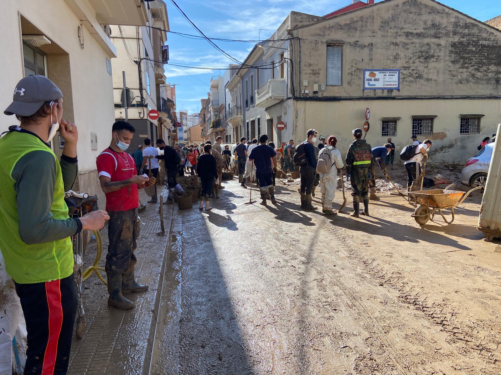 Vecinos, voluntarios y efectivos de emergencias retirando el barro en Catarroja