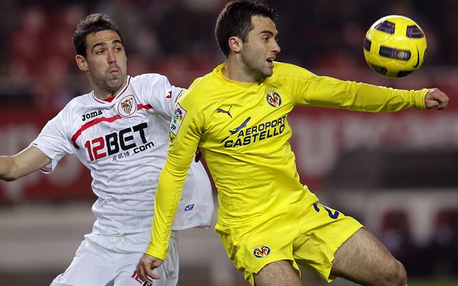 El defensa del Sevilla Fernando Navarro (i) pelea un balón con el delantero italiano del Villarreal, Giuseppe Rossi, durante el partido de vuelta de cuartos de final de la Copa del Rey que estos dos equipos juegan esta noche en el estadio Sánchez Pizjuán 