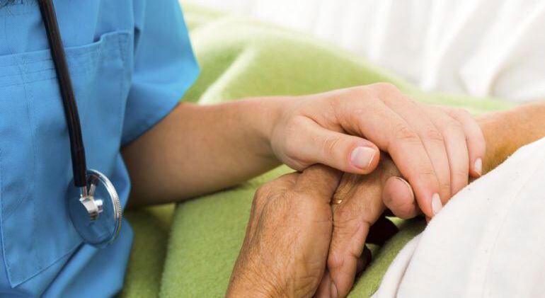 Imagen de un sanitario cogiendo la mano de un paciente.