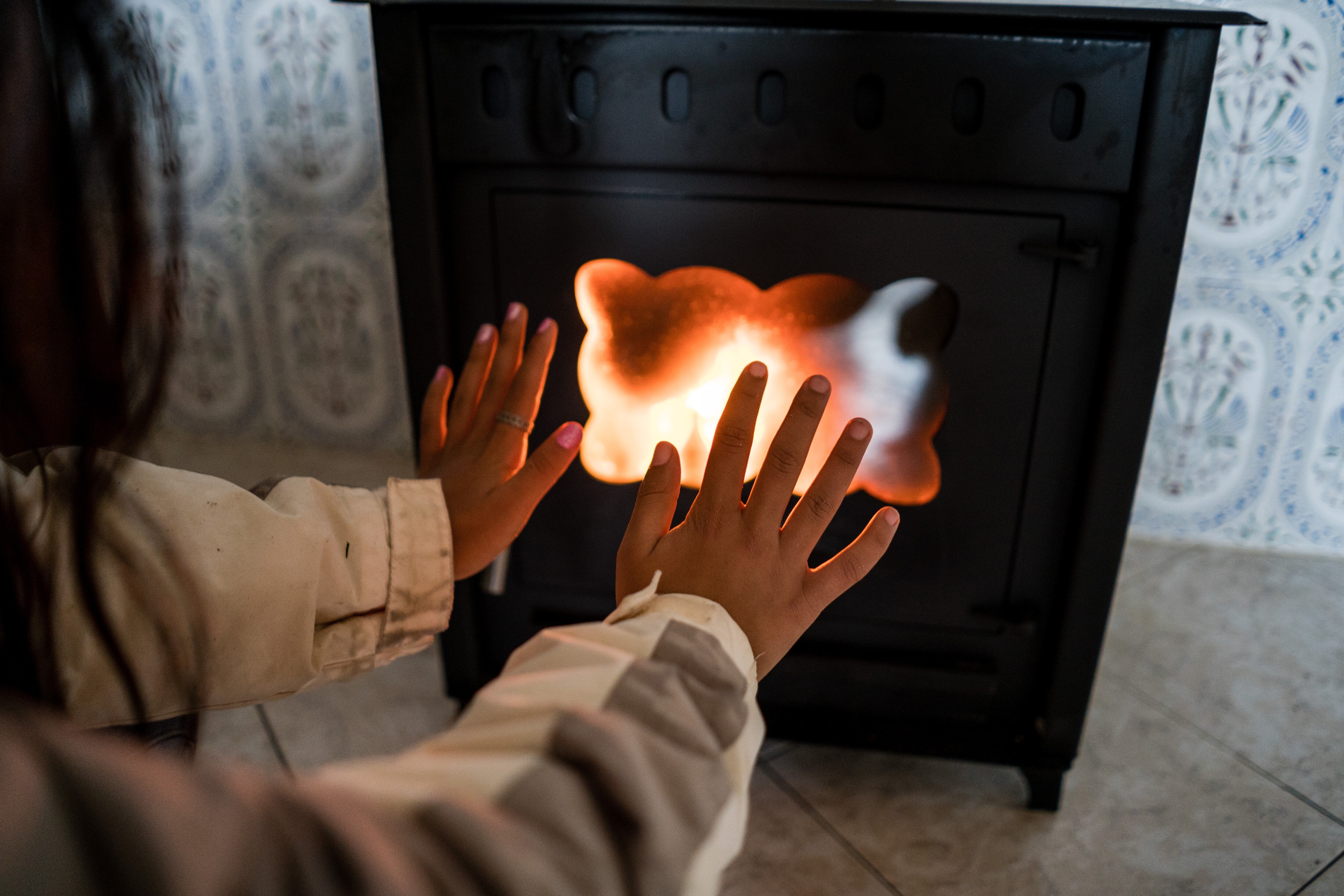 Una niña calienta sus manos en una chimenea de gas en la Cañada Real durante el temporal de Filomena