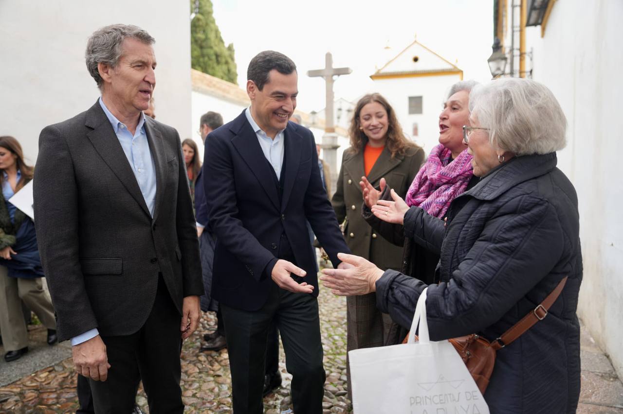 Alberto Núñez Feijóo junto a Juan Manuel Moreno, saludando a dos mujeres a las puertas de la residencia de la Fundación Hospital San Jacinto y Nuestra Señora de los Dolores en Córdoba.