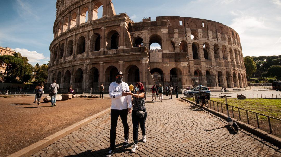 Dos personas con mascarilla junto al Coliseo en Roma.