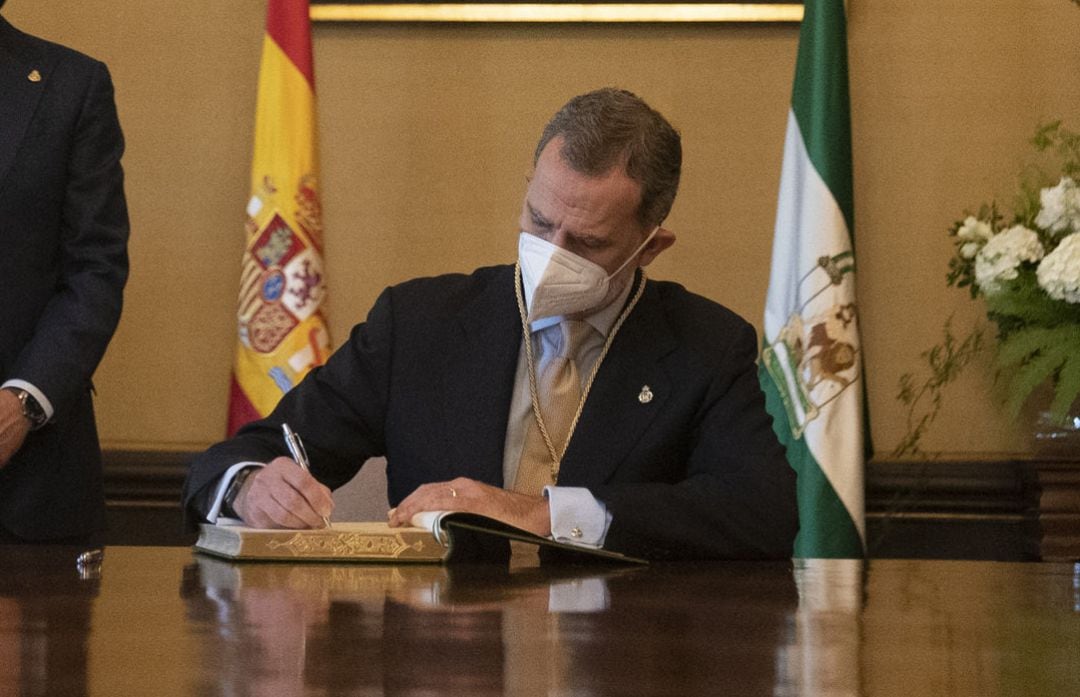 El  Rey Felipe VI, firma en el libro de honor ante la presencia de el presidente de la Junta de Andalucía, Juanma  Moreno, después del acto de entrega de  la Medalla de Honor de Andalucía, a 14 de junio del 2021 en el Palacio de San Telmo de Sevilla.