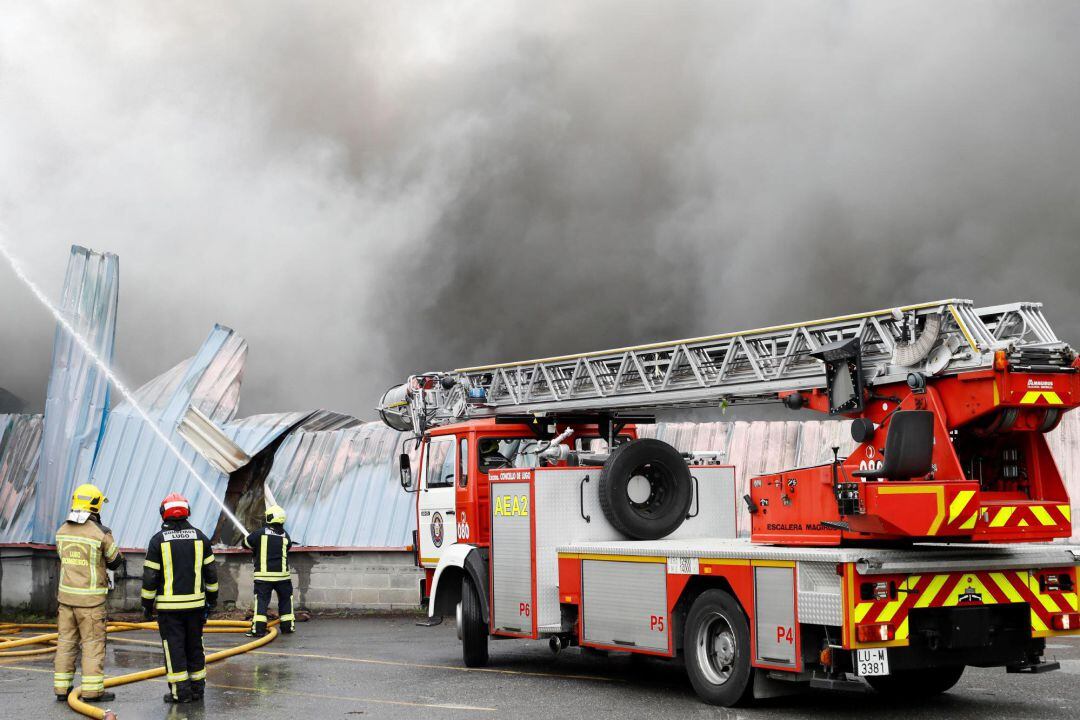 Una dotación del cuerpo de bomberos trabaja en las labores de extinción del incendio que ha afectado al menos a cuatro naves del parque empresarial de O Ceao (Lugo), que está ya controlado, después de seis horas de intenso trabajo de los bomberos, aunque 