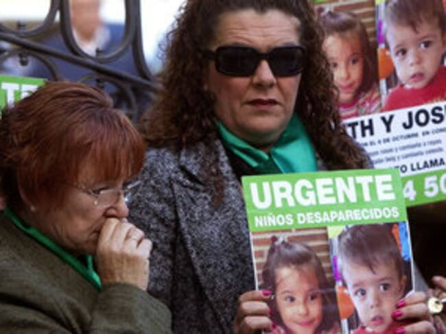 Dos mujeres portan carteles con fotografías de los niños onubenses Ruth y José Ortiz