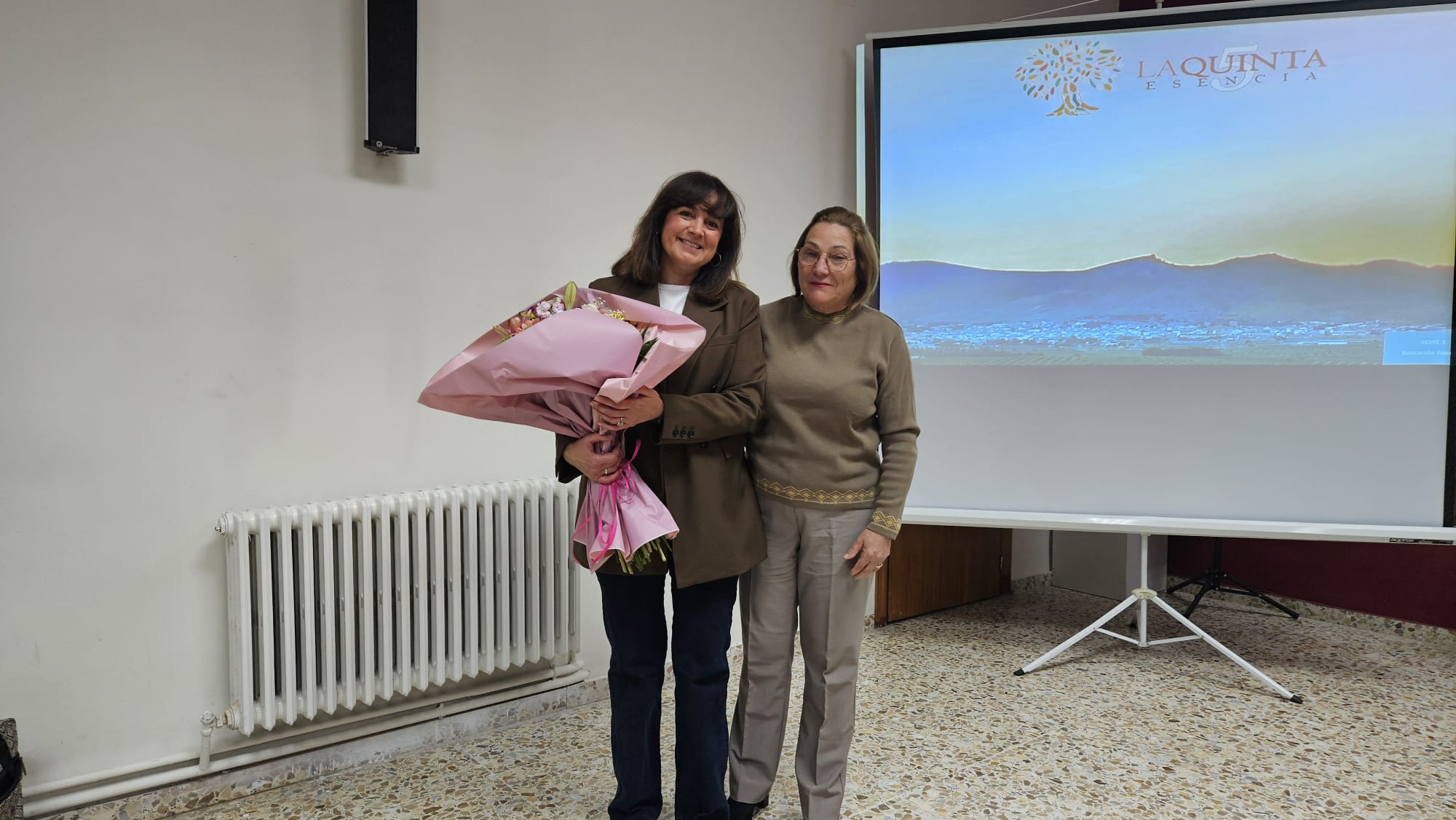La secretaria de la Junta Rectora de la Cooperativa, Isabel López, entrega un ramo de flores a la conferenciante. Adela Sierra