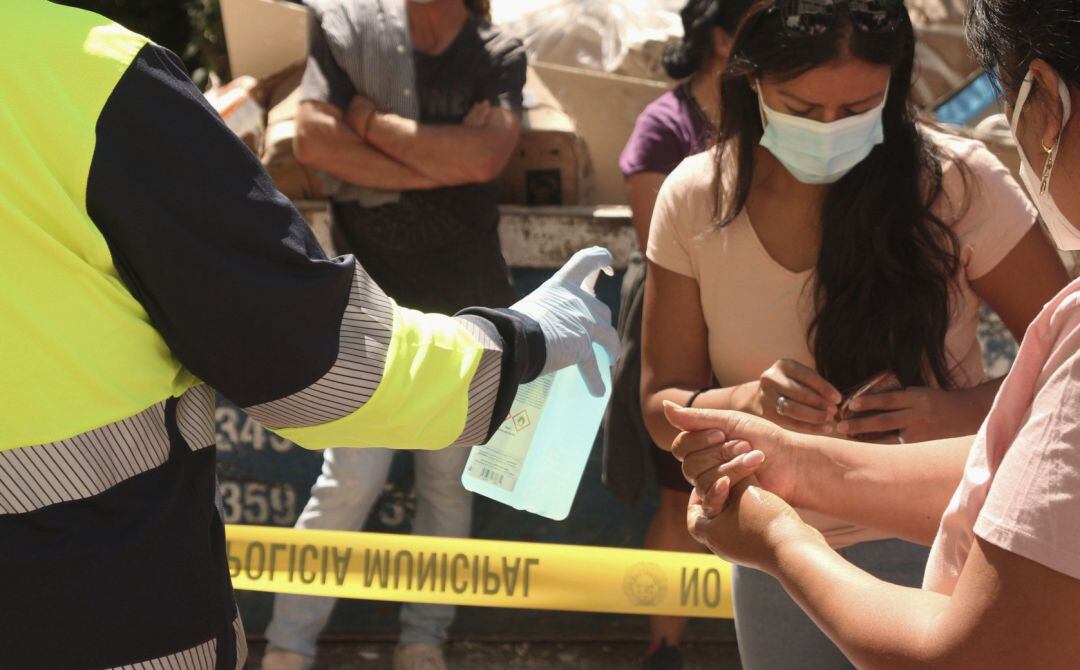 Un sanitario proporciona gel hidroalcohólico a varias personas.