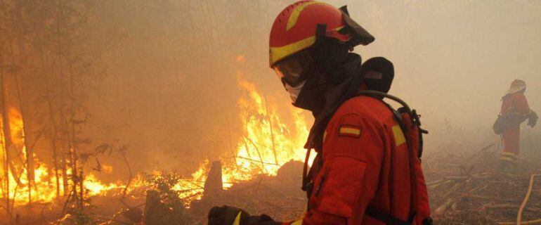 Un bombero tratando de extinguir las llamas del incendio de Santiago de Compostela