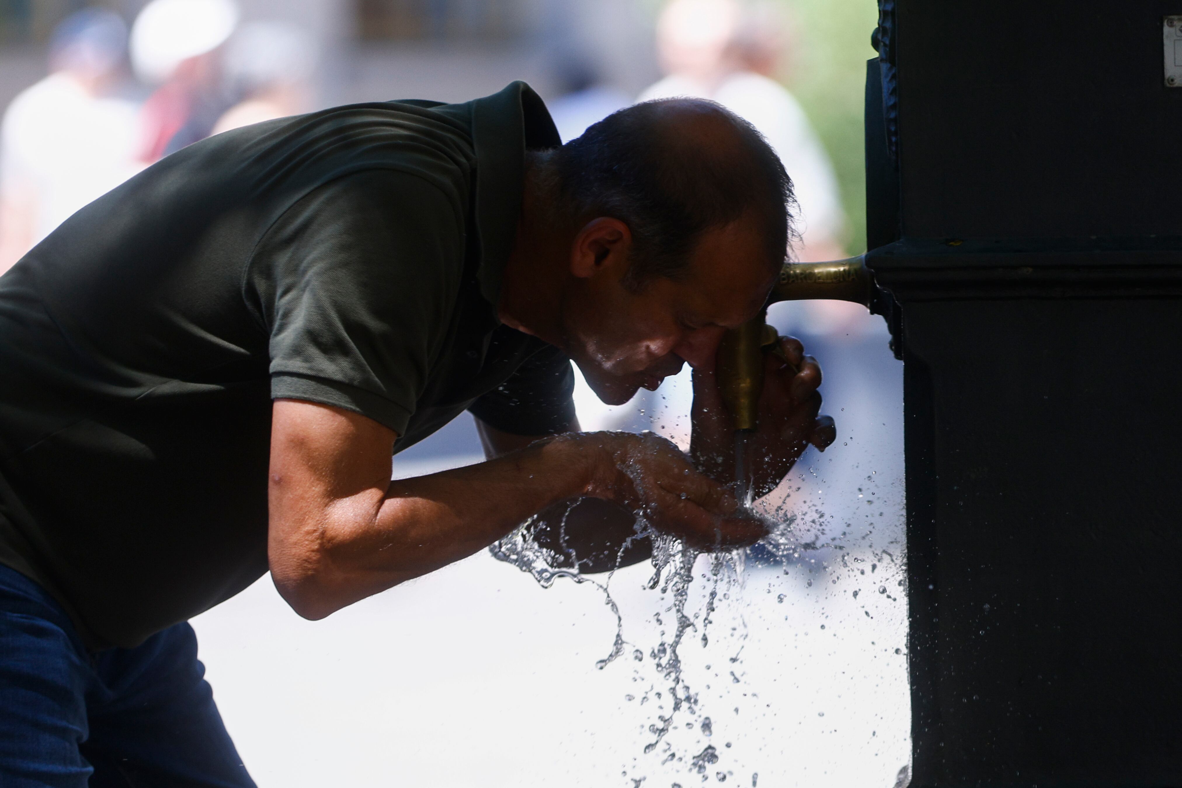 Imagen de archivo de un hombre refrescándose en una fuente.