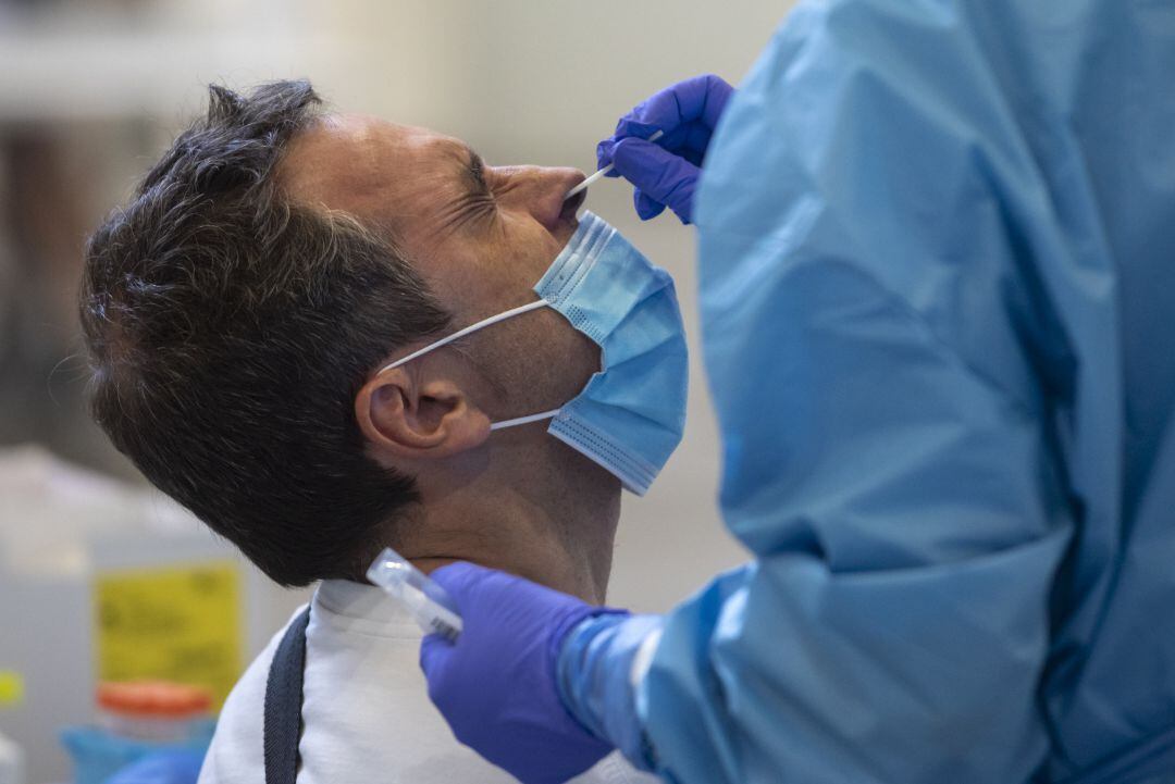 un hombre sometido a una prueba PCR por parte del personal sanitario. 