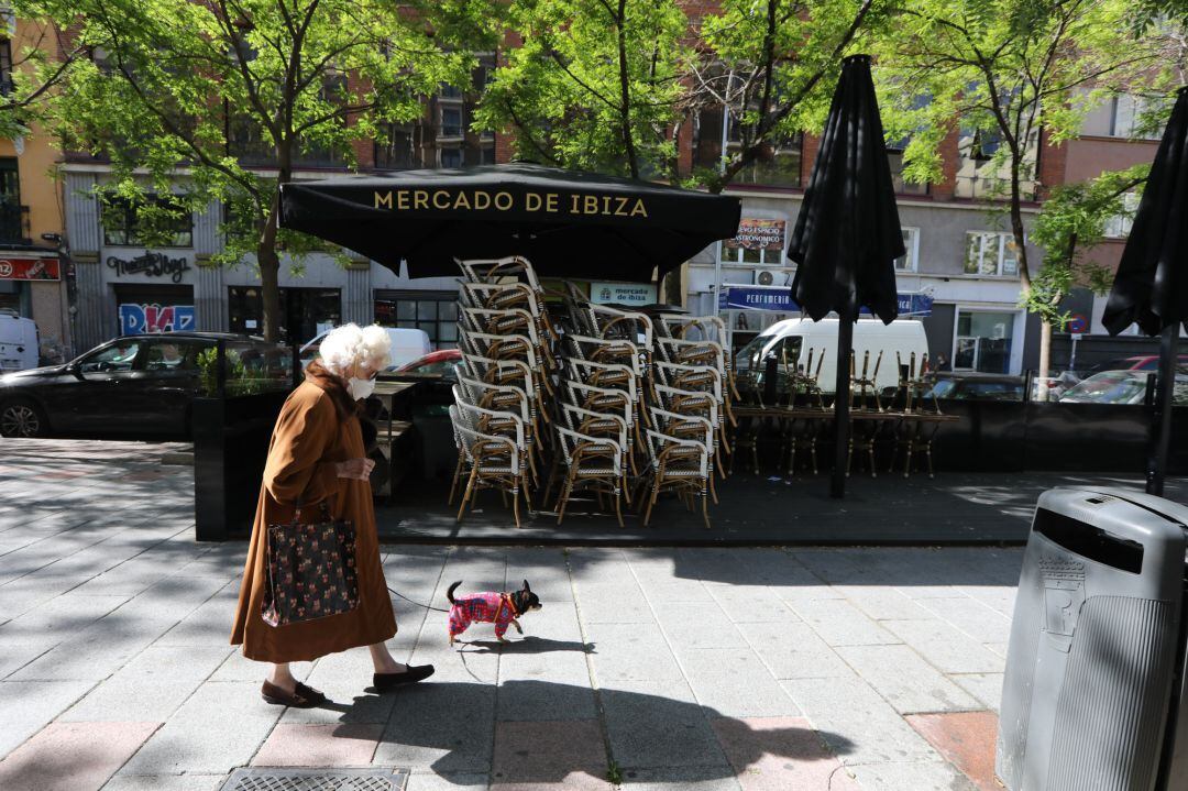 Una mujer pasa junto a una terraza cerrada de un bar en Madrid.