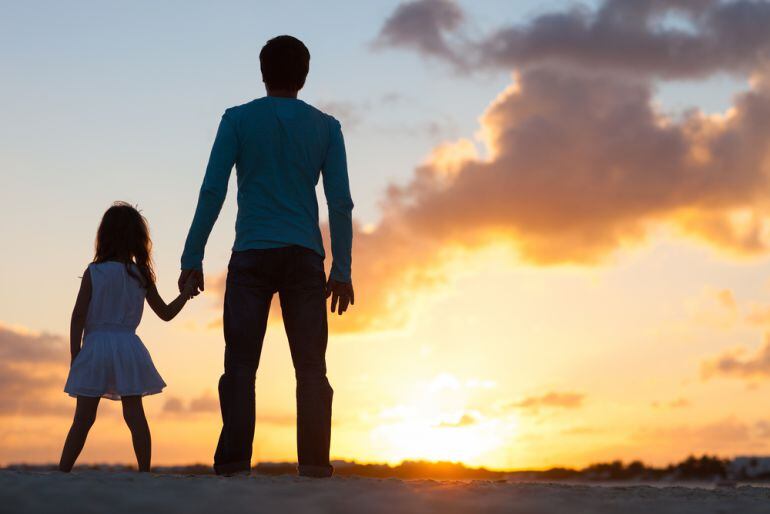 Un padre, junto a su hija, viendo el atardecer. 