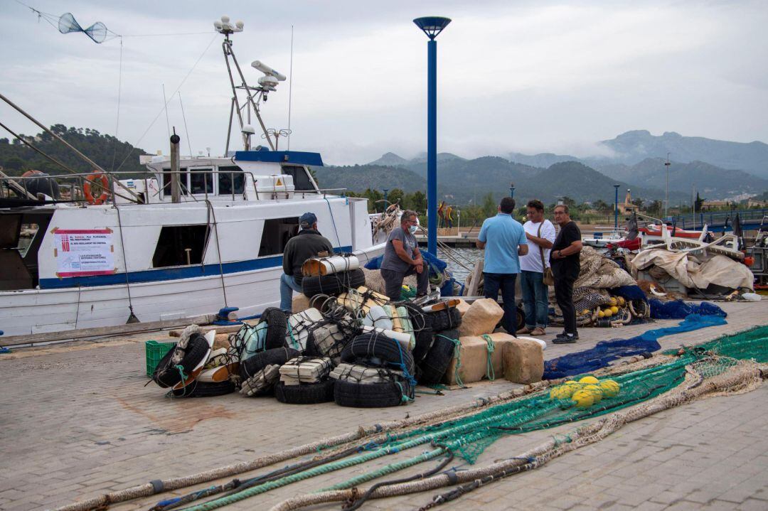 Varios personas congregadas junto a un barco de pesca amarrado en el Puerto de Andratx, Mallorca, este viernes, durante la jornada de paro de la flota pesquera de Baleares en protesta por el plan de gestión de la pesca aprobado por la Unión Europea.