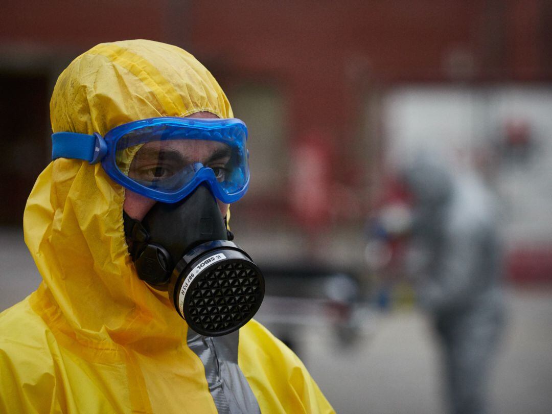 Un voluntario se protege con máscara, gafas y traje EPI