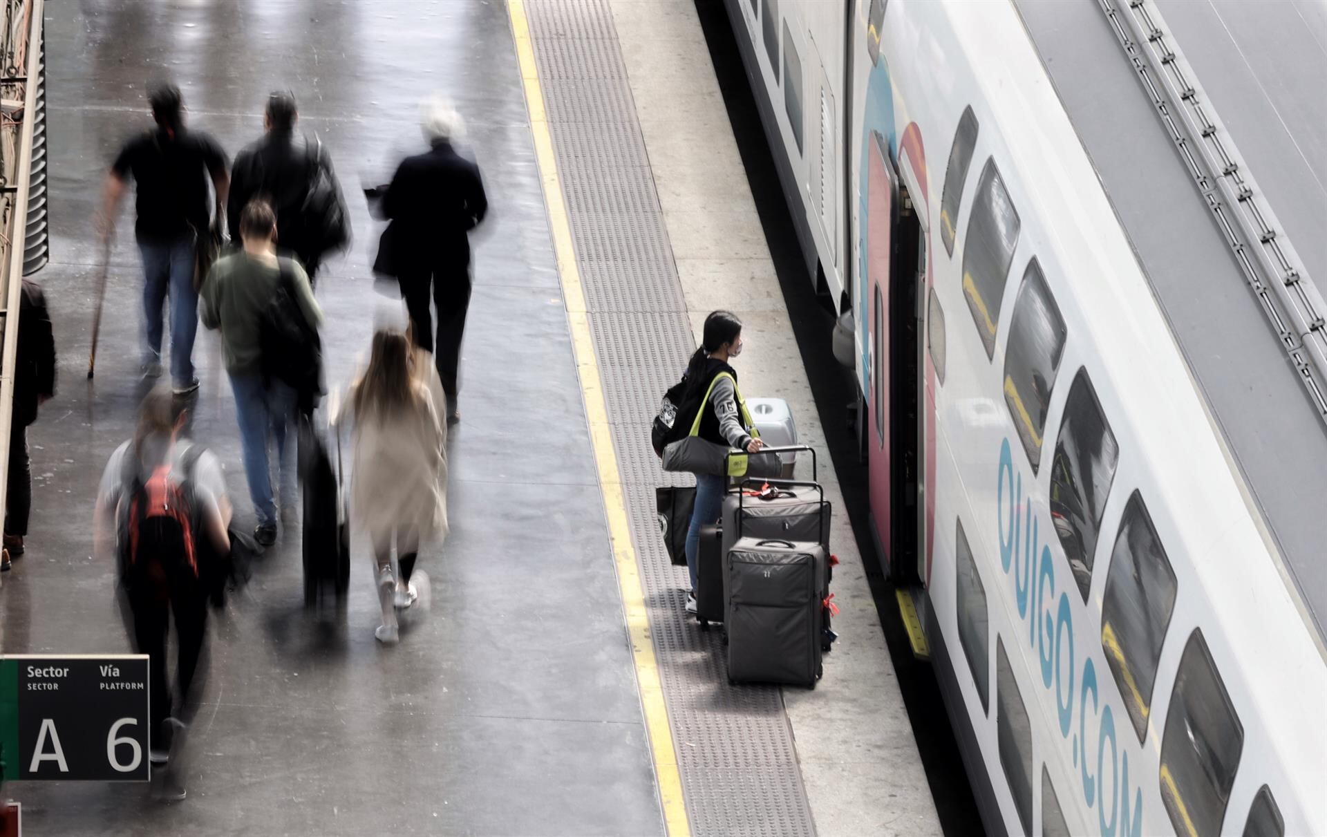 Varias personas, con maletas, en el andén antes de coger un tren de alta velocidad